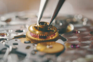 professional watchmaker repairer working on a vintage mechanism clock in a workshop copper